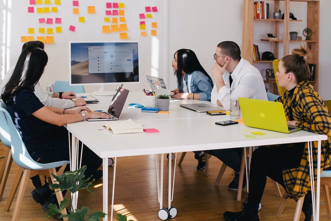 A team of five people in an office discussing and examining customer journey examples during a meeting